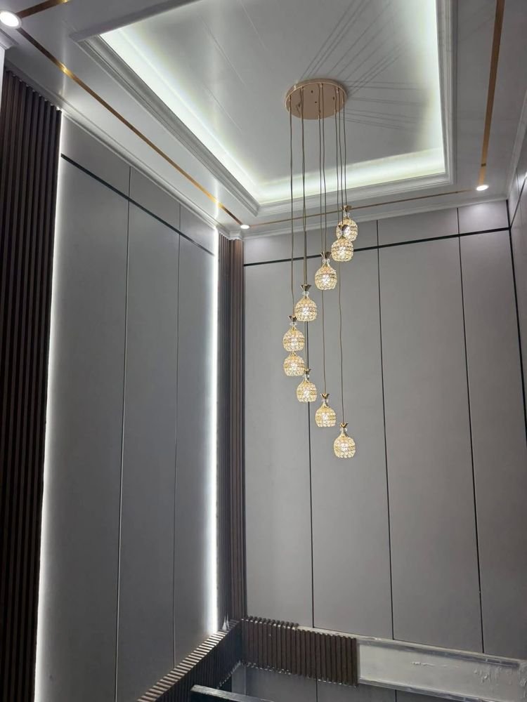 Lampu gantung kristal bertingkat di plafon panel kayu